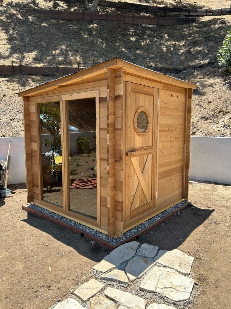 Custom cedar outdoor sauna with handcrafted wood door and poolside wellness retreat